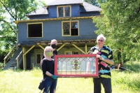 Curator L. Norman, Bjorn, and Bill Veltin holding up a stained glass window from the house.